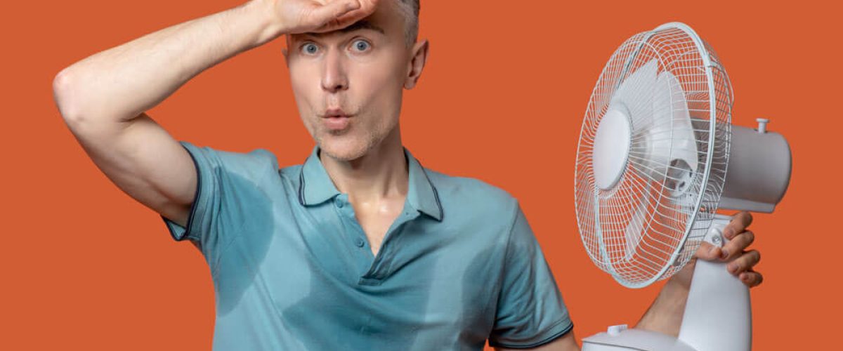 unbearable-heat-unhappy-man-wet-tshirt-touching-forehead-holding-fan-fleeing-heat